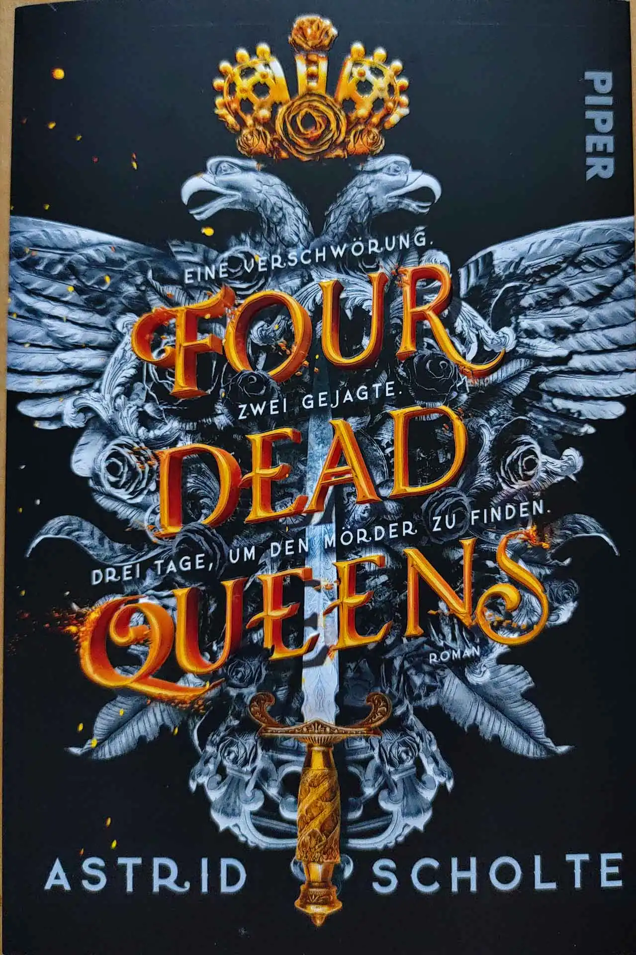 Das Cover des Buchs Four Dead Queens von Astrid Scholte, zeigt ein Emblem, bestehend aus zwei Adlern, einer Krone und einem Dolch auf dunklem Hintergrund.